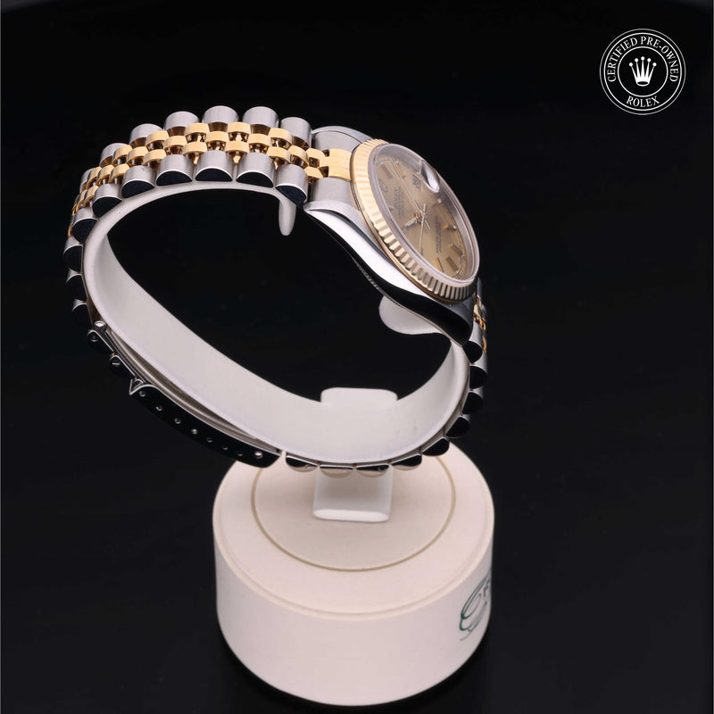 Rolex Datejust 31 with steel & yellow-gold Jubilee bracelet and champagne dial, on a cream presentation stand against a black background.Datejust 31