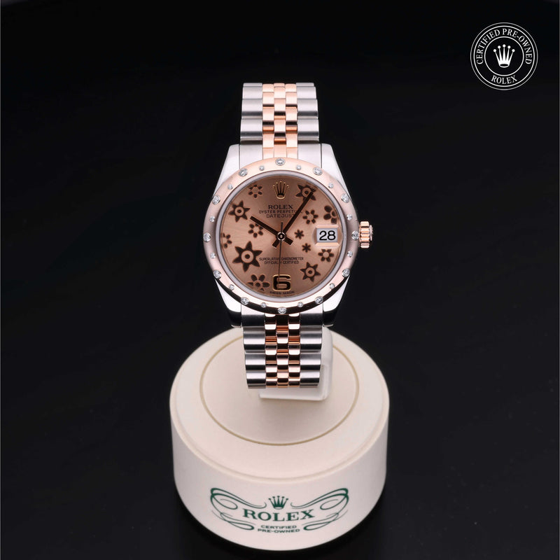 Rolex Datejust 31 in steel and Everose gold with gem-set bezel, floral motif dial and Jubilee bracelet on a black background.Datejust 31