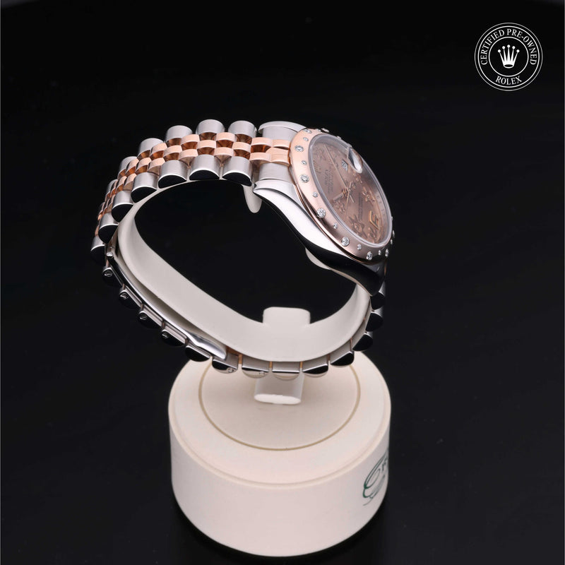 Rolex Datejust 31 in steel and Everose gold with gem-set bezel, floral motif dial and Jubilee bracelet on a black background.Datejust 31