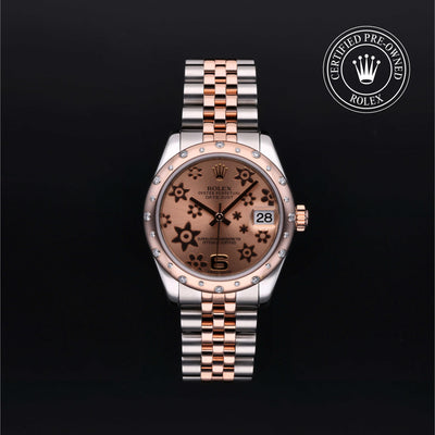 Rolex Datejust 31 in steel and Everose gold with gem-set bezel, floral motif dial and Jubilee bracelet on a black background.