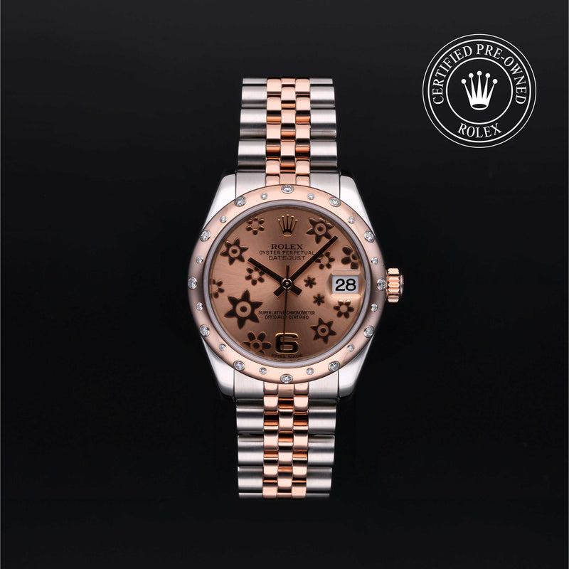 Rolex Datejust 31 in steel and Everose gold with gem-set bezel, floral motif dial and Jubilee bracelet on a black background.