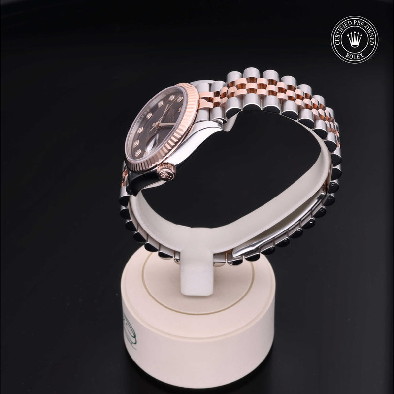 Rolex Datejust 31 with steel & Everose gold Jubilee bracelet and chocolate, diamond-set dial on a cream presentation stand against a black background.Datejust 31