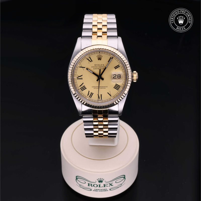 Rolex Datejust 36 with steel & yellow-gold Jubilee bracelet and champagne dial, on a cream presentation stand against a black background.Datejust 36