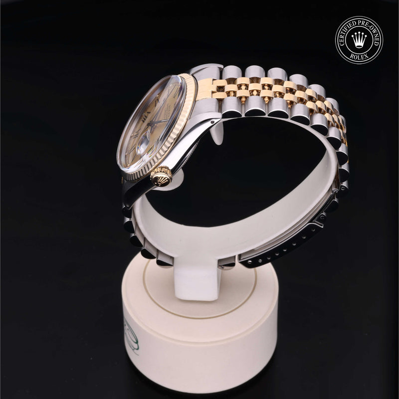 Rolex Datejust 36 with steel & yellow-gold Jubilee bracelet and champagne dial, on a cream presentation stand against a black background.Datejust 36