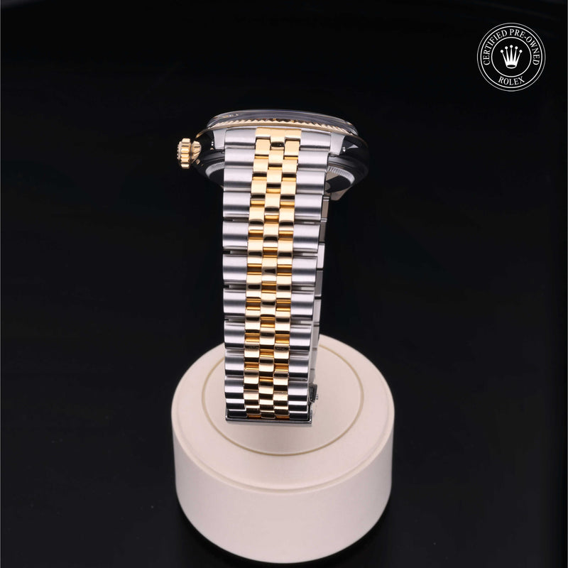 Rolex Datejust 36 with steel & yellow-gold Jubilee bracelet and champagne dial, on a cream presentation stand against a black background.Datejust 36