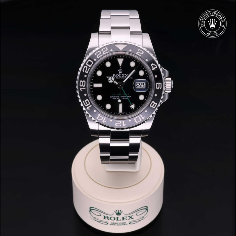 Rolex GMT-Master II with steel Oyster bracelet and black dial, on a cream presentation stand against a black background.GMT-Master II