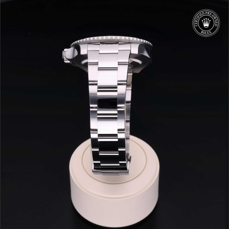 Rolex GMT-Master II with steel Oyster bracelet and black dial, on a cream presentation stand against a black background.GMT-Master II