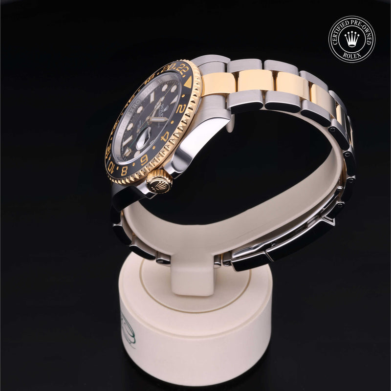 Rolex GMT-Master II watch with steel and yellow-gold Oyster bracelet and black dial on a black background.GMT-Master II