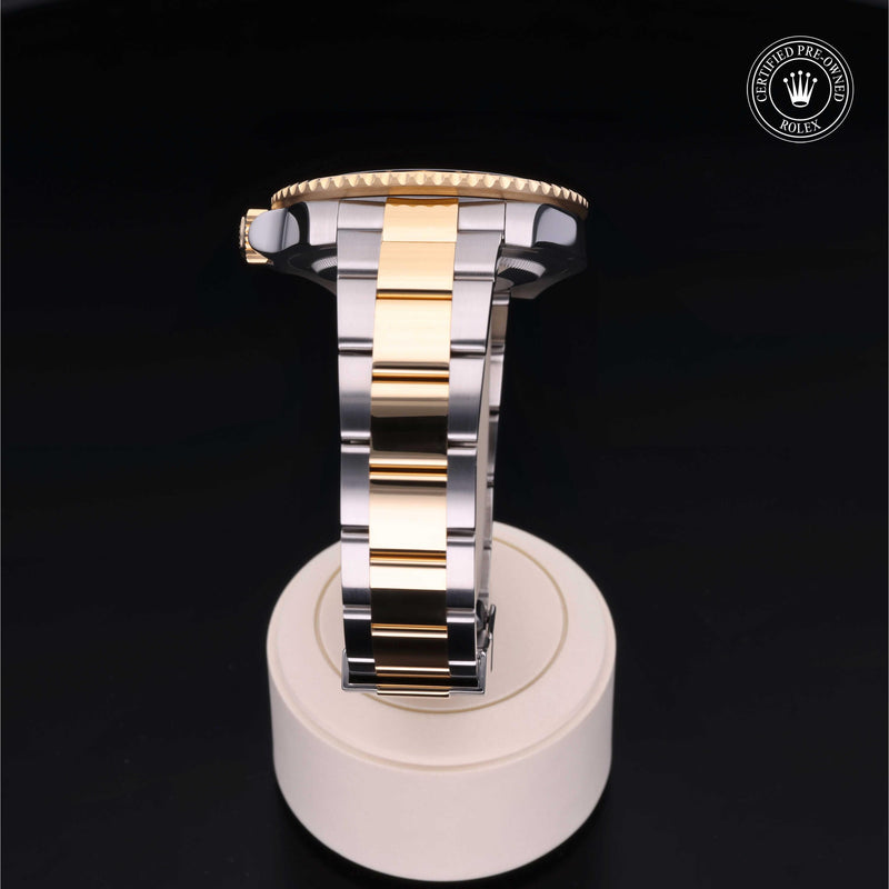 Rolex GMT-Master II watch with steel and yellow-gold Oyster bracelet and black dial on a black background.GMT-Master II