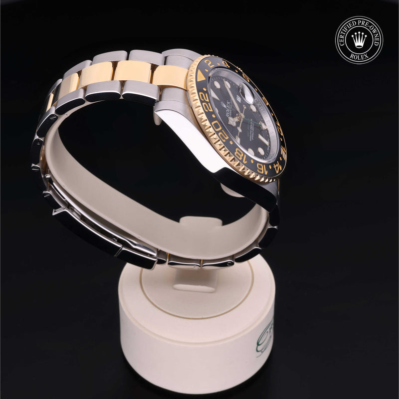 Rolex GMT-Master II watch with steel and yellow-gold Oyster bracelet and black dial on a black background.GMT-Master II