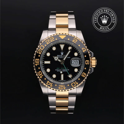 Rolex GMT-Master II watch with steel and yellow-gold Oyster bracelet and black dial on a black background.