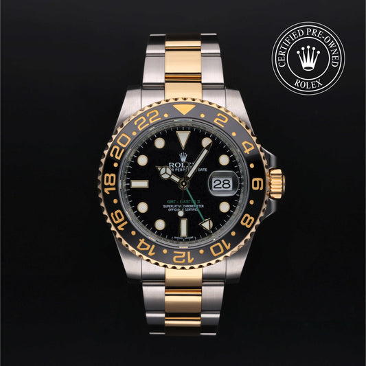 Rolex GMT-Master II watch with steel and yellow-gold Oyster bracelet and black dial on a black background.