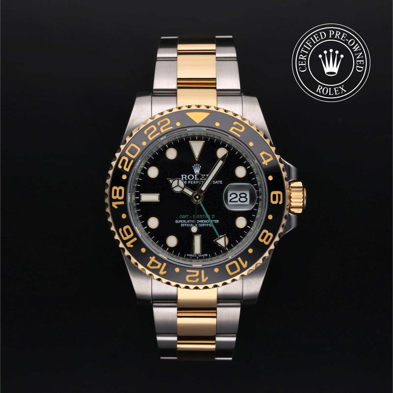 Rolex GMT-Master II watch with steel and yellow-gold Oyster bracelet and black dial on a black background.