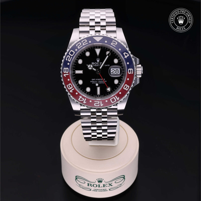 Rolex GMT-Master II with Jubilee bracelet, blue & red bezel and black dial, on a cream presentation stand against a black background.GMT-Master II