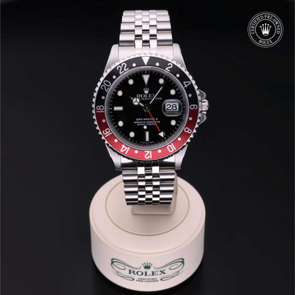 Rolex GMT-Master II with Jubilee bracelet, red and black bezel and black dial on a presentation stand against a black background.