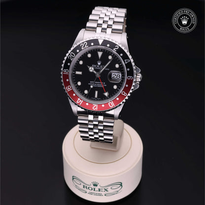 Rolex GMT-Master II with Jubilee bracelet, red and black bezel and black dial on a presentation stand against a black background.