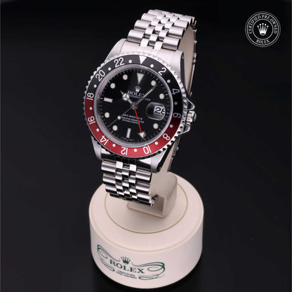 Rolex GMT-Master II with Jubilee bracelet, red and black bezel and black dial on a presentation stand against a black background.