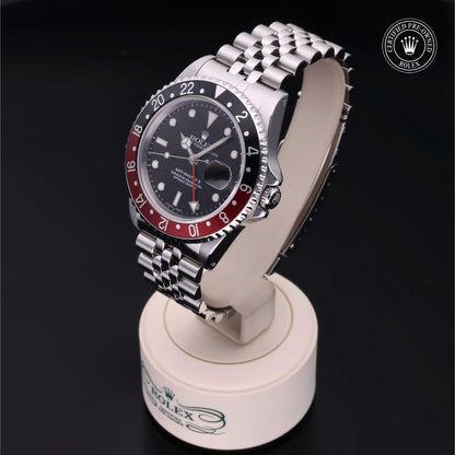 Rolex GMT-Master II with Jubilee bracelet, red and black bezel and black dial on a presentation stand against a black background.