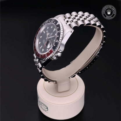 Rolex GMT-Master II with Jubilee bracelet, red and black bezel and black dial on a presentation stand against a black background.