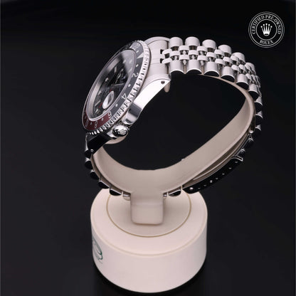 Rolex GMT-Master II with Jubilee bracelet, red and black bezel and black dial on a presentation stand against a black background.