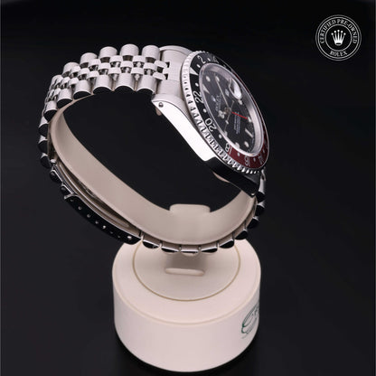 Rolex GMT-Master II with Jubilee bracelet, red and black bezel and black dial on a presentation stand against a black background.