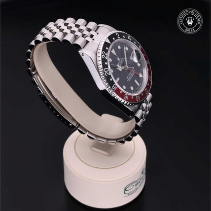 Rolex GMT-Master II with Jubilee bracelet, red and black bezel and black dial on a presentation stand against a black background.