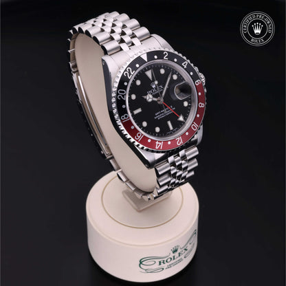 Rolex GMT-Master II with Jubilee bracelet, red and black bezel and black dial on a presentation stand against a black background.