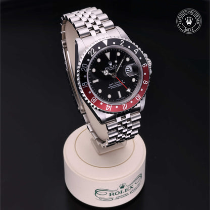 Rolex GMT-Master II with Jubilee bracelet, red and black bezel and black dial on a presentation stand against a black background.