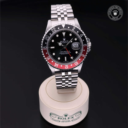 Rolex GMT-Master II with Jubilee bracelet, red and black bezel and black dial on a presentation stand against a black background.
