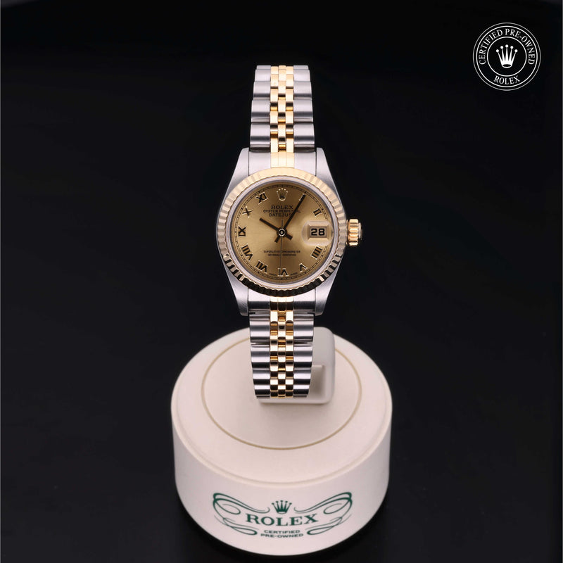Rolex Lady-Datejust 26 with steel & yellow gold Jubilee bracelet and champagne dial on a cream presentation stand against a black background.Lady-Datejust 26