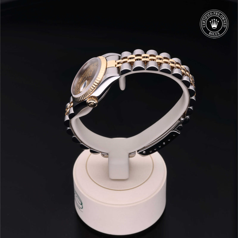 Rolex Lady-Datejust 26 with steel & yellow gold Jubilee bracelet and champagne dial on a cream presentation stand against a black background.Lady-Datejust 26