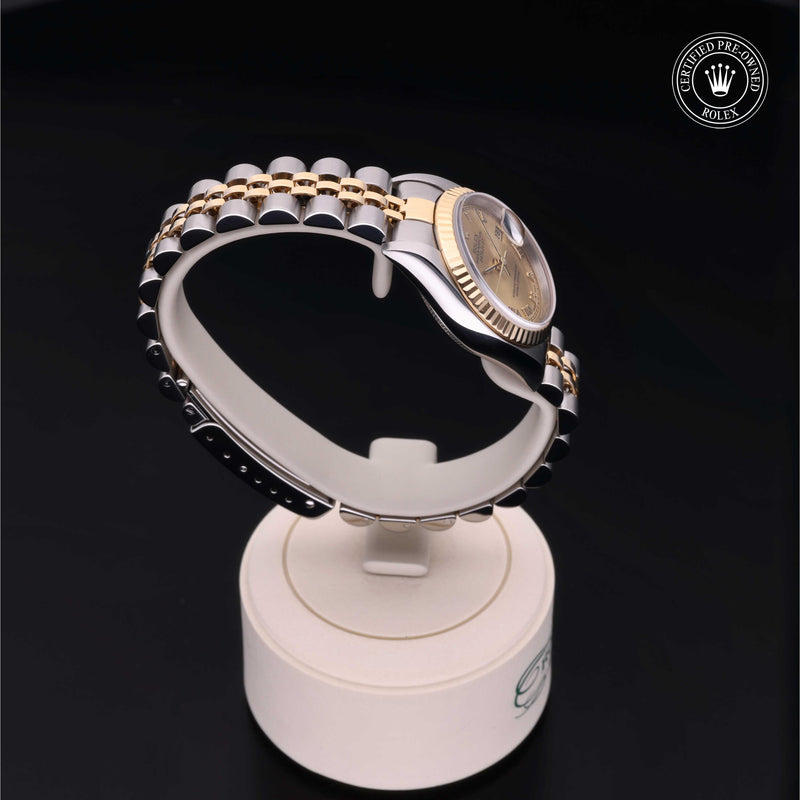 Rolex Lady-Datejust 26 with steel & yellow gold Jubilee bracelet and champagne dial on a cream presentation stand against a black background.Lady-Datejust 26
