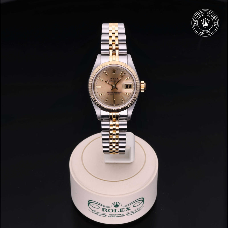 Rolex Lady-Datejust 26 with steel and yellow-gold Jubilee bracelet and champagne dial, on a cream presentation stand against a black background.Lady-Datejust 26