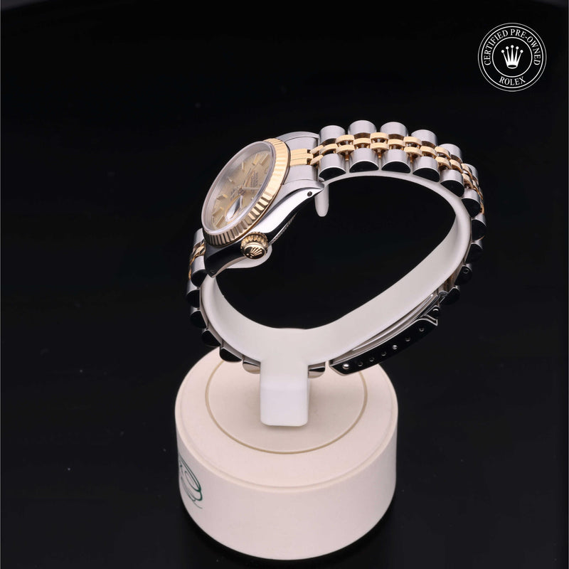 Rolex Lady-Datejust 26 with steel and yellow-gold Jubilee bracelet and champagne dial, on a cream presentation stand against a black background.Lady-Datejust 26