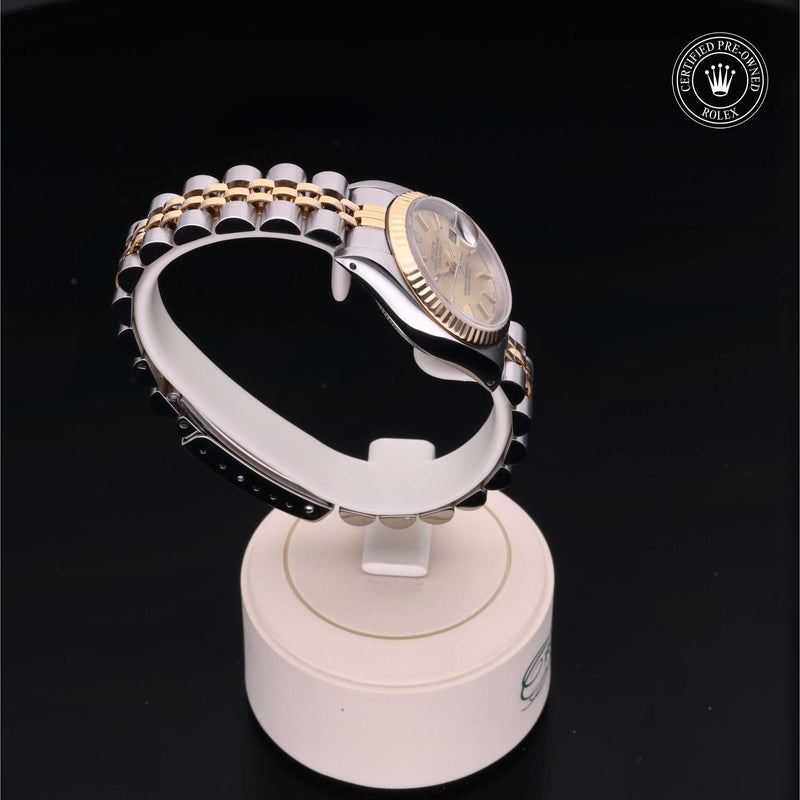 Rolex Lady-Datejust 26 with steel and yellow-gold Jubilee bracelet and champagne dial, on a cream presentation stand against a black background.Lady-Datejust 26