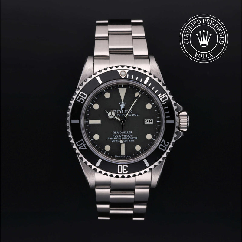Rolex Sea-Dweller watch with a steel Oyster bracelet and black dial on a black background.