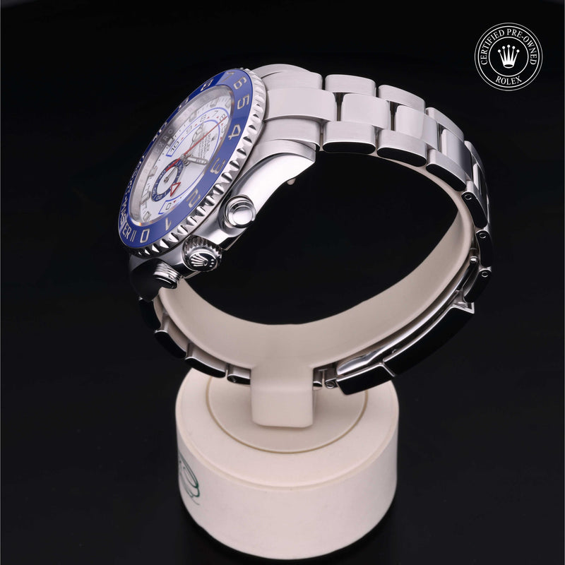 Rolex Yacht-Master II watch with a steel Oyster bracelet and white dial on a cream stand with a black background.Yacht-Master II