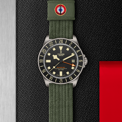 TUDOR Pelagos FXD GMT with 42mm titanium case, green fabric strap and black dial on a black background.