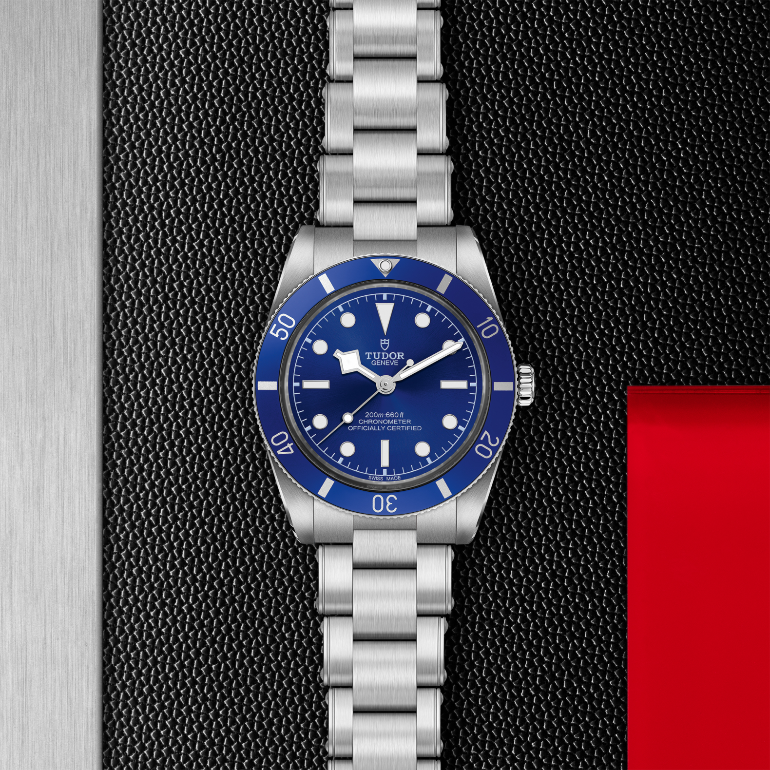 Tudor Black Bay 54 watch with a steel bracelet and blue dial on a black textured background.