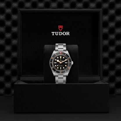 Tudor Black Bay 58 watch with a steel bracelet and black dial in a black box against a black background.