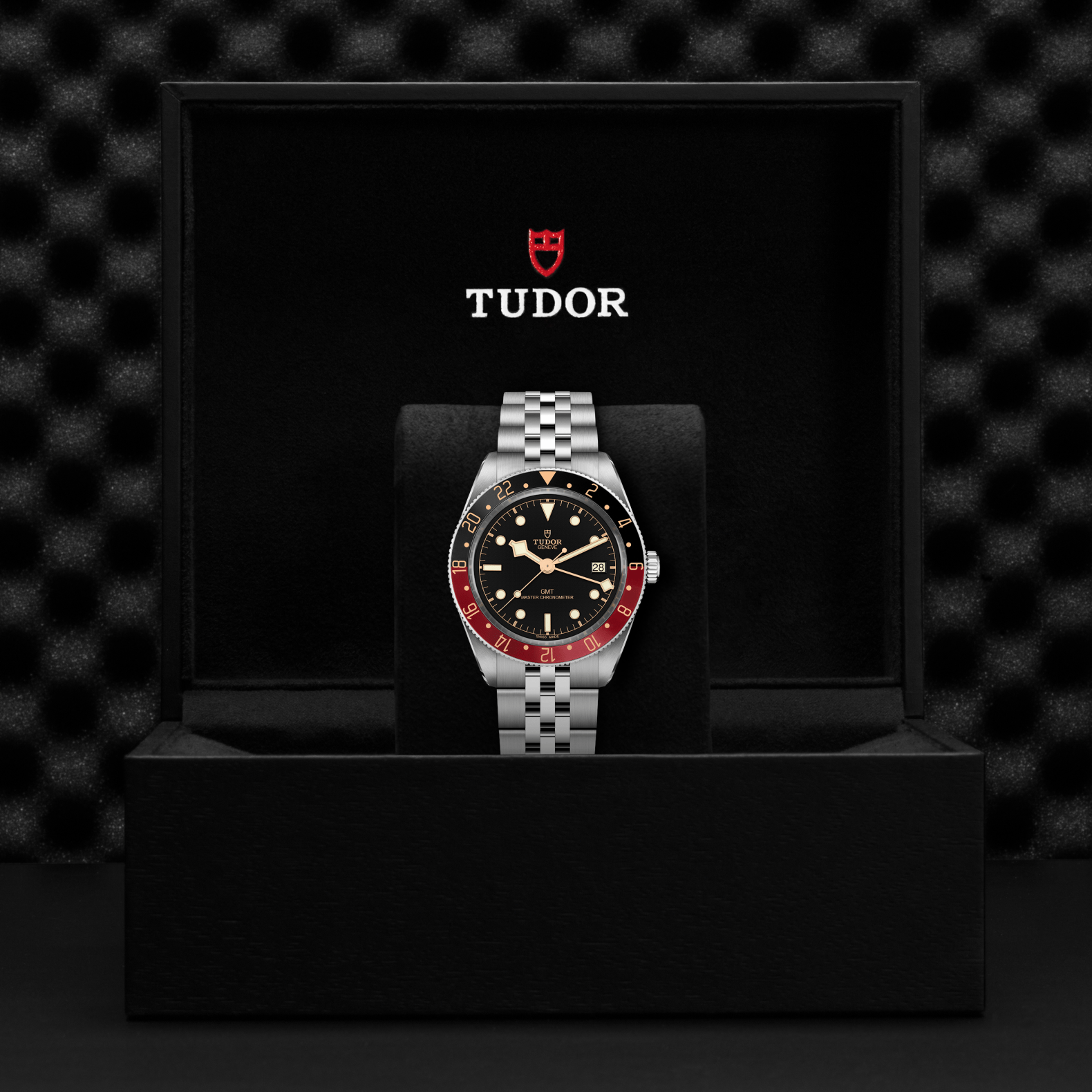 Tudor Black Bay 58 watch with a steel bracelet and black dial in a black box against a black background.