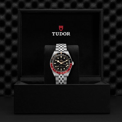 Tudor Black Bay 58 watch with a steel bracelet and black dial in a black box against a black background.