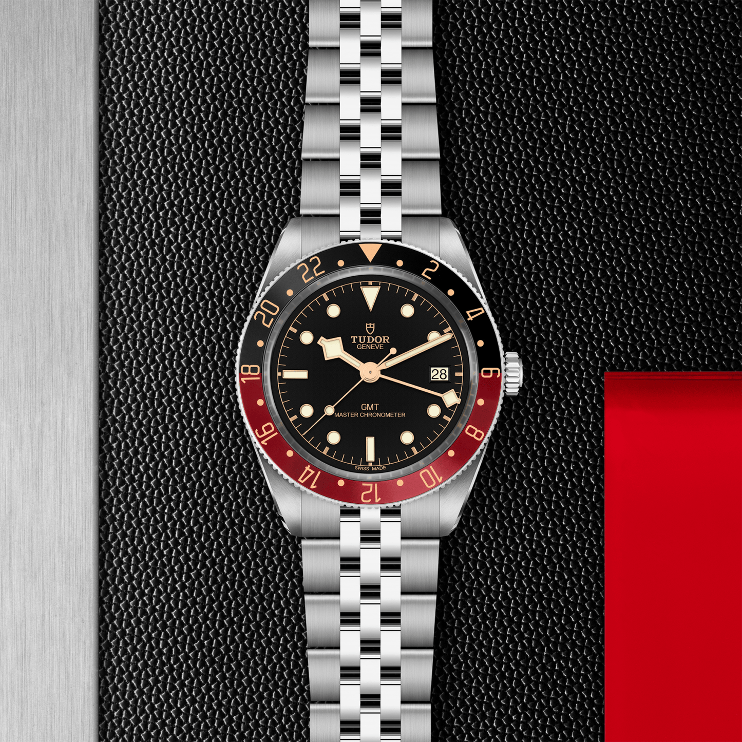 Tudor Black Bay 58 GMT watch with a steel bracelet and black dial on a black textured background.