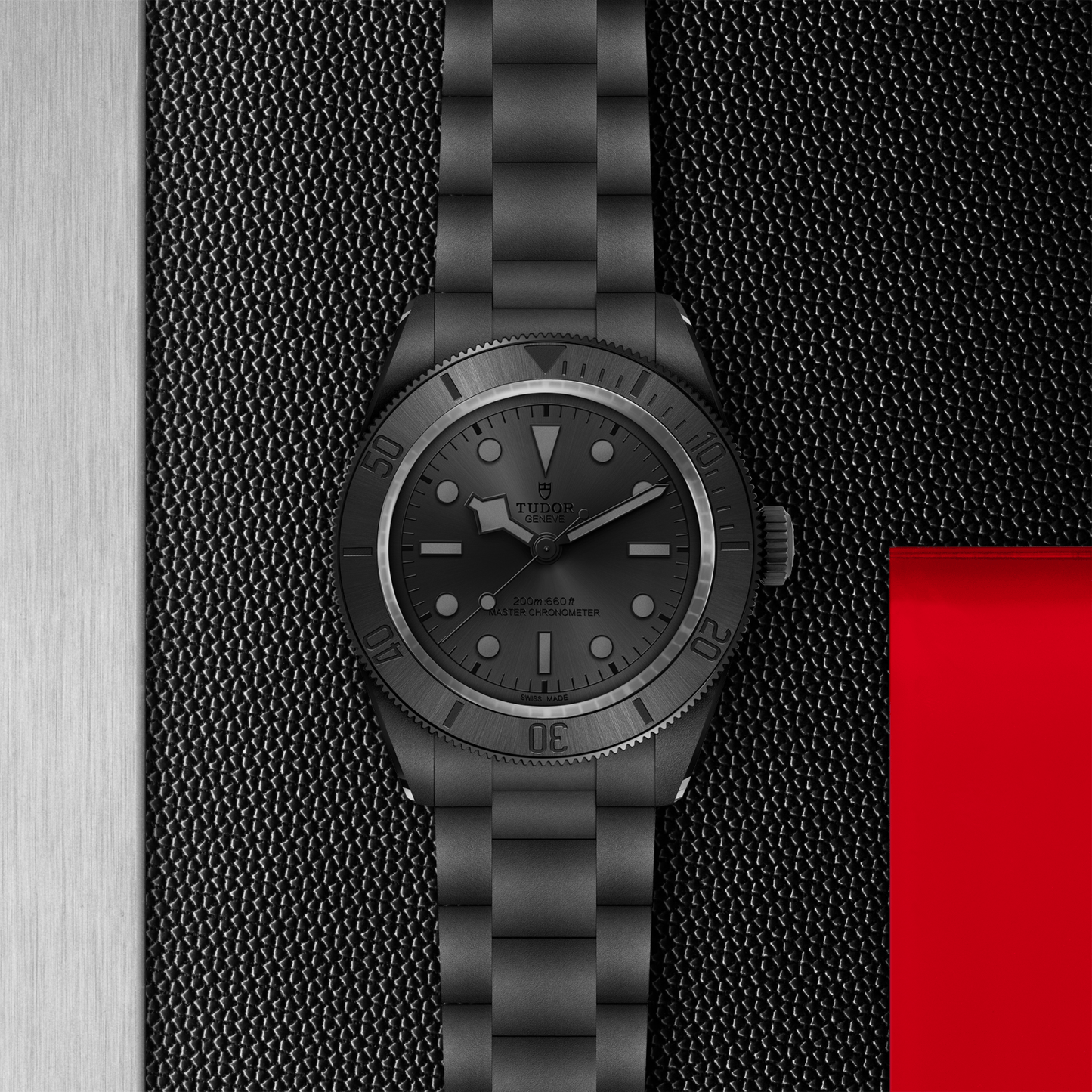 Tudor Black Bay Ceramic watch on bracelet with a black dial on a black textured background.